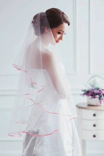 Mooie bruid met mode bruiloft hairstyle - op witte achtergrond. Portret van de jonge vrouw. Studio opname. Meisje sluier over haar gezicht — Stockfoto
