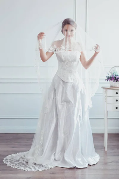 Hermosa novia con peinado de boda de moda - sobre fondo blanco. Retrato de mujer joven. Grabado en estudio. Velo de niña sobre su cara — Foto de Stock