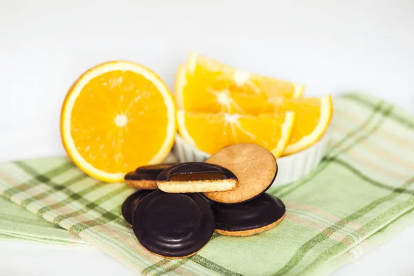 Heaps of Chocolate Chip Cookies with orange on green napkin and white background. — Stock Photo, Image