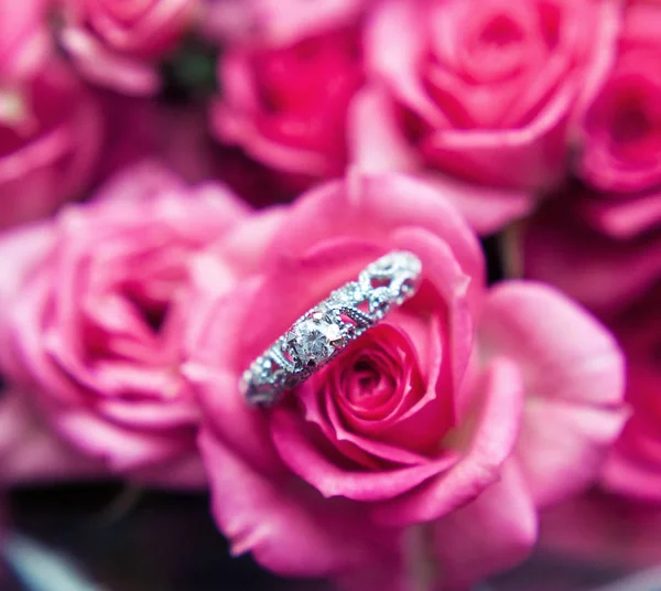 Sparkling diamond engagement ring in one of small pink roses great for valentines — Stock Photo, Image