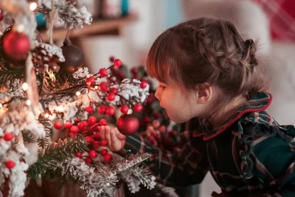 Happy little smiling girl with christmas toy near a xmas tree — Stock Photo, Image