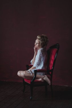 bir marsala iç sandalyede oturan zarif beyaz elbise içinde utangaç ve genç güzel gelin