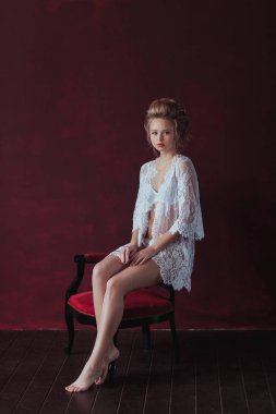 bir marsala iç sandalyede oturan zarif beyaz elbise içinde utangaç ve genç güzel gelin