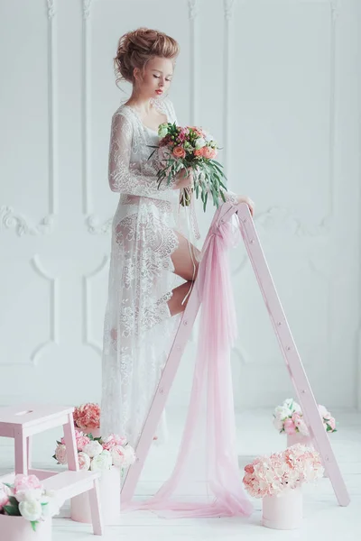 Linda noiva com buquê de casamento em pé na escada decorada. Olha para baixo. — Fotografia de Stock