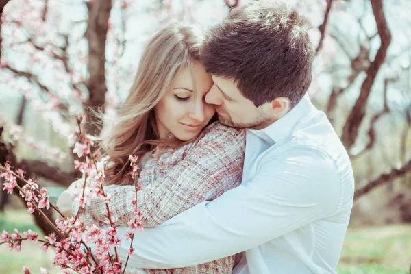 Et ungt, lykkelig par utendørs. kjærlig mann og kvinne på tur på vår blomstrende park – stockfoto