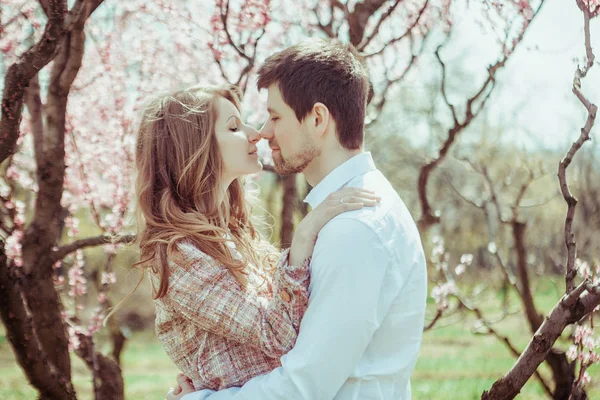 Et ungt, lykkelig par utendørs. kjærlig mann og kvinne på tur på vår blomstrende park – stockfoto