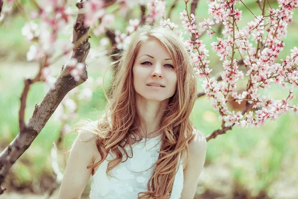 Bela menina loira primavera na árvore florescente — Fotografia de Stock