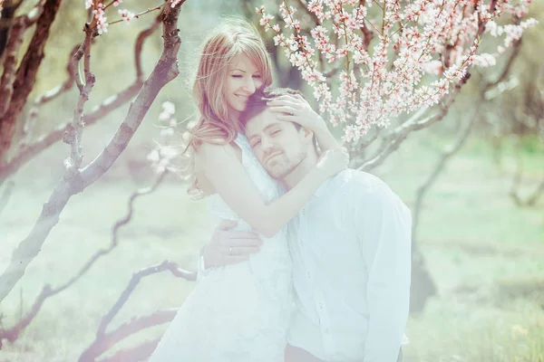 Joven pareja feliz enamorada al aire libre. hombre y mujer cariñosos en un paseo en el parque floreciente de primavera —  Fotos de Stock