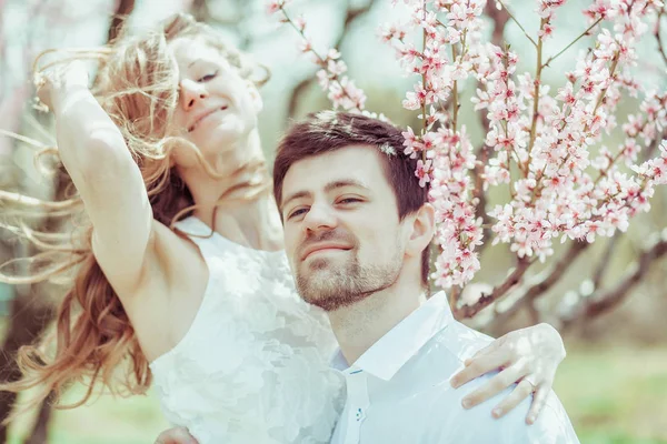 Et ungt, lykkelig par utendørs. kjærlig mann og kvinne på tur på vår blomstrende park – stockfoto