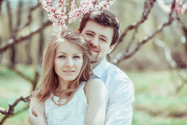 Joven pareja feliz enamorada al aire libre. hombre y mujer cariñosos en un paseo en el parque floreciente de primavera —  Fotos de Stock