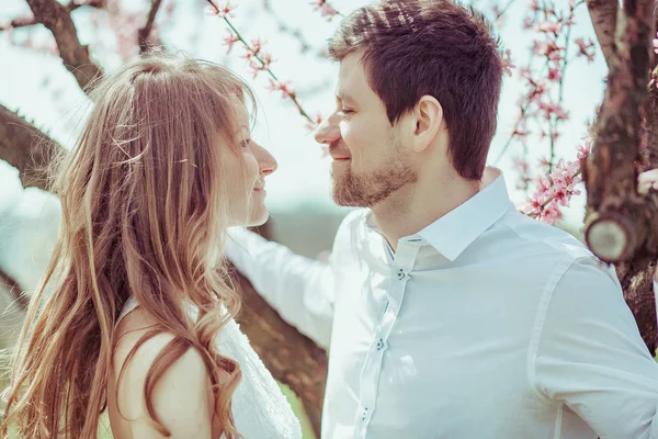 Et ungt, lykkelig par utendørs. kjærlig mann og kvinne på tur på vår blomstrende park – stockfoto