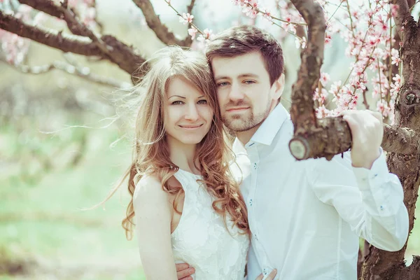 Joven pareja feliz enamorada al aire libre. hombre y mujer cariñosos en un paseo en el parque floreciente de primavera —  Fotos de Stock