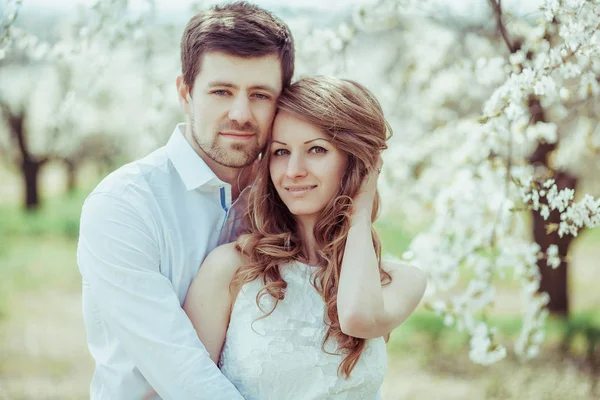Et ungt, lykkelig par utendørs. kjærlig mann og kvinne på tur på vår blomstrende park – stockfoto