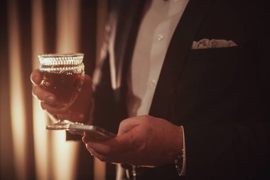 Genç sakallı adam vintage bir bardak kırmızı şarap ile karşı ışık tutan Kızıl. siyah arka plan üzerinde. adam telefonda arıyorum