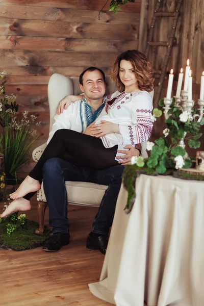 Hermosa joven pareja embarazada vestida en estilo ucraniano nacional en el estudio. Maternidad y concepto de felicidad familiar —  Fotos de Stock