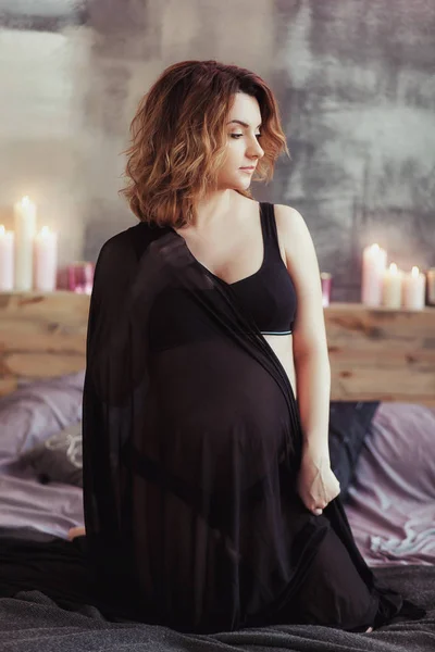 Schwangere auf dem Bett in einem Zimmer mit Kerzen — Stockfoto