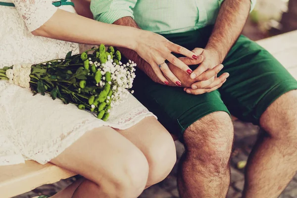 Cropped shot of young couple holding hands while sitting together outdoor. Focus on ring — Stock Photo, Image