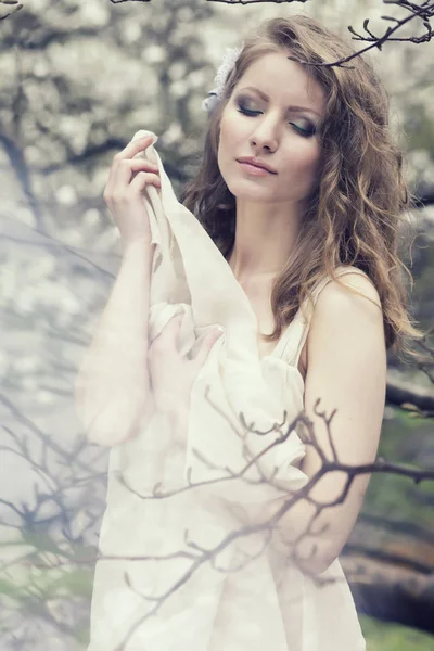 Beautiful blonde with beautiful hairstyle in vintage blue dress in a lush spring garden magnolia — Stock Photo, Image