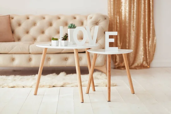 A palavra Amor em letras brancas no fundo do volume interior. Sofá branco bege e mesa de café no quarto — Fotografia de Stock