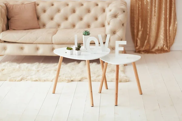 A palavra Amor em letras brancas no fundo do volume interior. Sofá branco bege e mesa de café no quarto — Fotografia de Stock