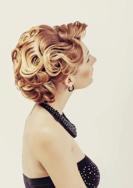 Hermosa mujer con el pelo rubio usando pequeño vestido negro tocando su vista del cuello desde la espalda en blanco —  Fotos de Stock
