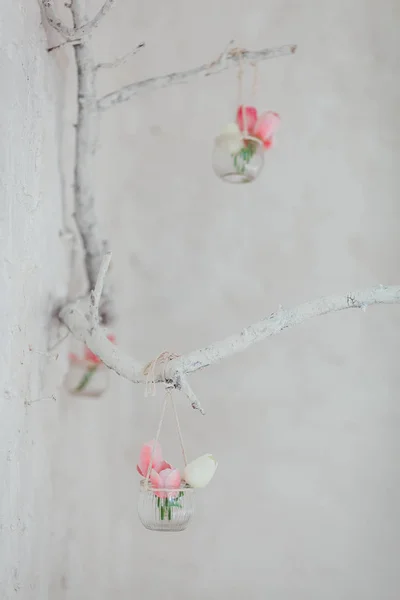 Los tulipanes en los floreros cuelgan de la rama decorativa en la pared con los ladrillos blancos —  Fotos de Stock