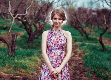 Ağaçlar arasında duran çekici genç kadın. Arka ışık.