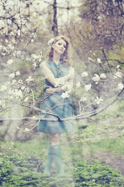 Loira bonita com penteado bonito em vestido azul vintage em uma magnólia jardim de primavera exuberante — Fotografia de Stock