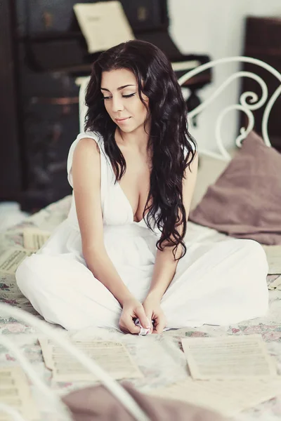 Mulher de vestido branco com notas sentadas em sua cama. Conceito romântico — Fotografia de Stock