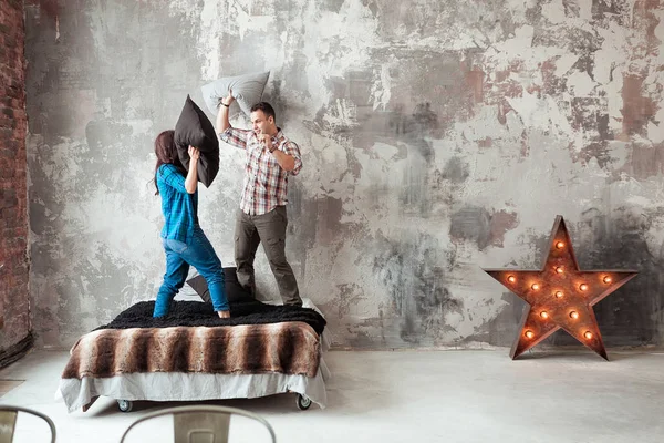 Ungt par kämpar kuddar i loft stil sovrummet — Stockfoto