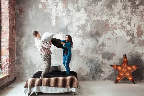 Ungt par kämpar kuddar i loft stil sovrummet — Stockfoto