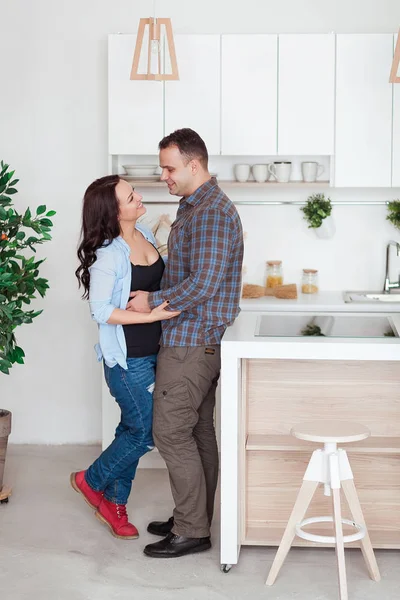 Счастливая пара обнимается в белом лофте на кухне. — стоковое фото