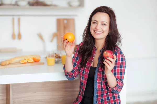 Aufnahme einer dunkelhaarigen kaukasischen Frau, die Äpfel mit Orangen vergleicht — Stockfoto
