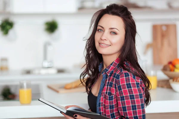 Café da manhã - Livro de leitura de mulher sorridente na cozinha branca, suco de laranja fresco — Fotografia de Stock