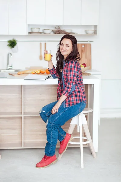 Café da manhã - Livro de leitura de mulher sorridente na cozinha branca, suco de laranja fresco — Fotografia de Stock