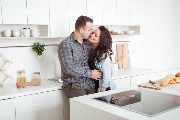 Glückliches Paar, das sich in der weißen Loft-Küche umarmt — Stockfoto