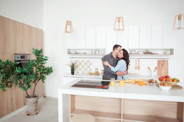 Счастливая пара обнимается в белом лофте на кухне. — стоковое фото
