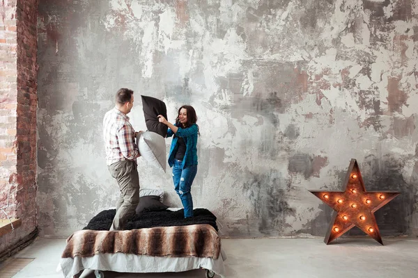 Ungt par kämpar kuddar i loft stil sovrummet — Stockfoto