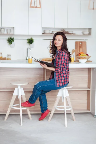 Desayuno - Mujer sonriente leyendo libro en cocina blanca, zumo de naranja fresco —  Fotos de Stock