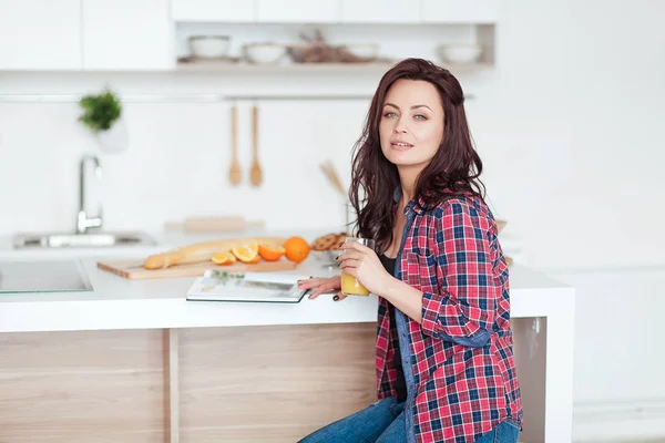 Desayuno - Mujer sonriente leyendo libro en cocina blanca, zumo de naranja fresco —  Fotos de Stock