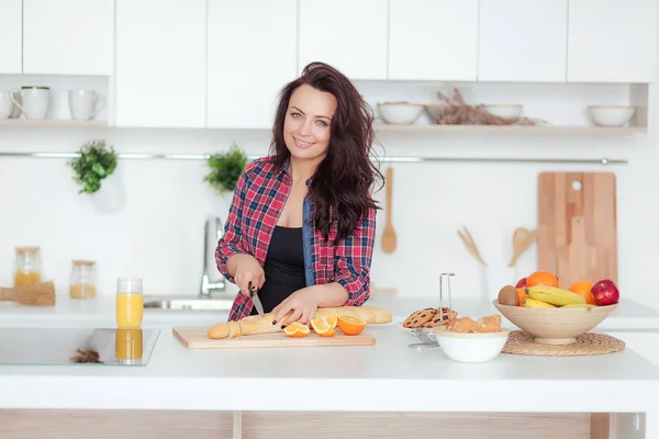 Feliz hermosa joven womancuts una baguette en el kithen — Foto de Stock