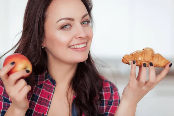 Diet. Dieting concept. Healthy Food. Beautiful Young Woman choosing between Fruits and Sweets. Weight Loss Stock Image