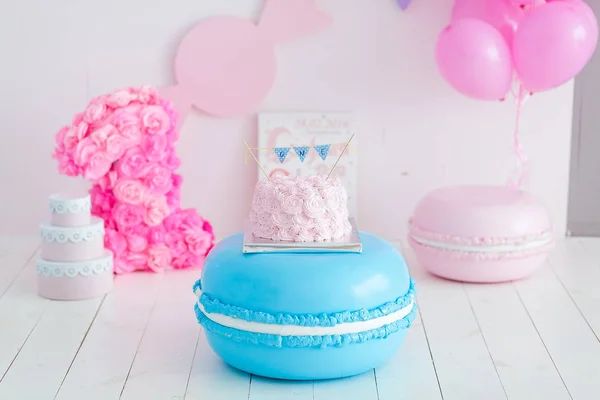 first birthday smash the cake. A pink cake stands on a large blue macaroon. First birthday