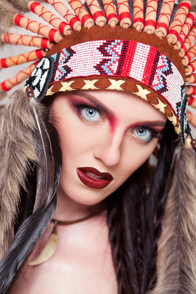 Mujer india con maquillaje tradicional y tocado mirando a la cámara. Mujer india de piel roja sobre fondo blanco con una cucaracha en la cabeza — Foto de Stock