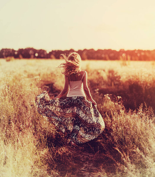 Красивая блондинка на цветочном поле на закате
