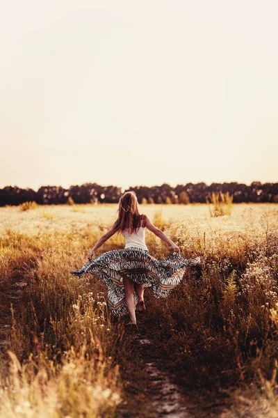 Hermosa dama rubia en el campo de flores al atardecer —  Fotos de Stock