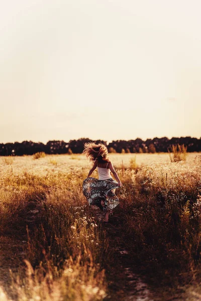 Mooie blonde dame in bloem veld bij zonsondergang — Stockfoto