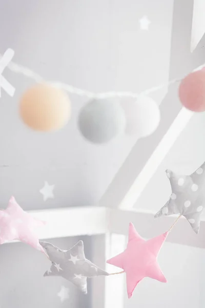 Cama de bebé con guirnalda de molino. Guirnalda de estrellas rosadas y grises en la sala de niños — Foto de Stock