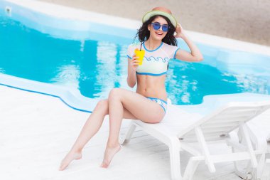 Kokteyl bardağına yakın Yüzme Havuzu bir şezlong üzerinde güneşte tüyler ürpertici olan kadın portresi. Tatil kavramı