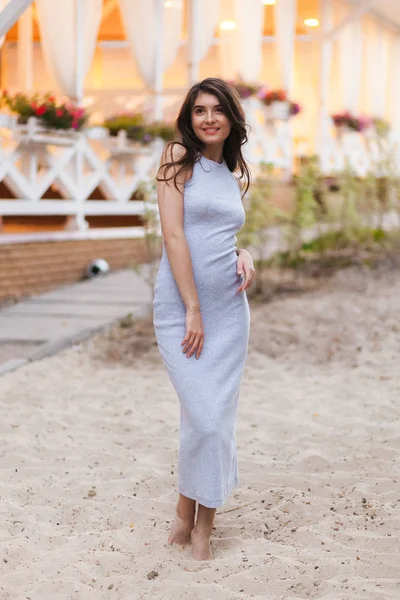 Elegant pretty slim woman in long beach dress posing near luxury resort near the beach . — Stock Photo, Image